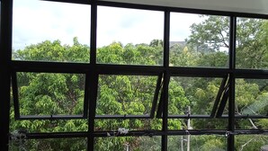 A room with large windows, a ceiling fan, and two wooden chairs. - Eden Grand (Dambulla)