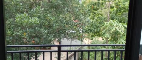 A balcony with two wooden tables and chairs, surrounded by a black metal railing.