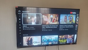 A YouTube interface on a television screen with multiple video thumbnails, including a drama titled "Kokomoo 3" and a show called "The Guest." - Miraph Apartment (Abuja)