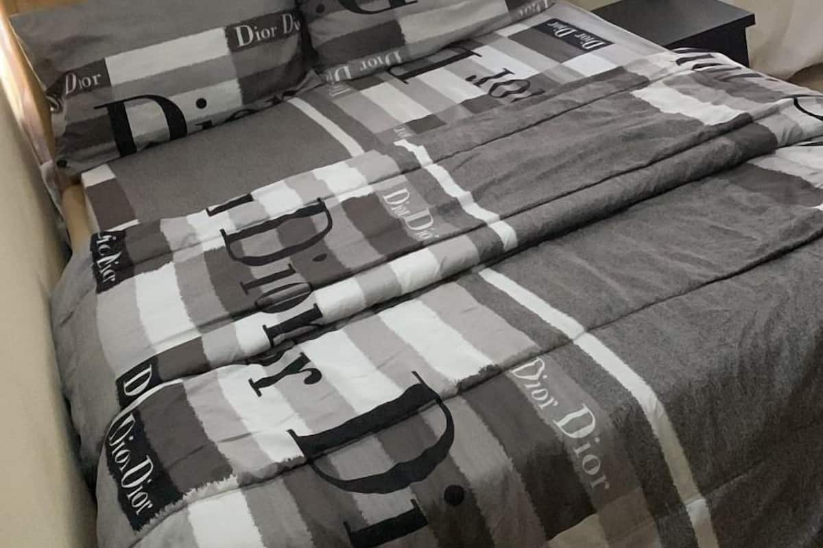 Una cama con cabecera, dos almohadas y una manta.