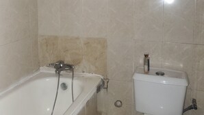 A bathroom with a bathtub, toilet, and sink. - Miraph Apartment (Abuja)