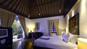 A hotel room with a bed, a desk, a TV, and a window with curtains. - Aventus Luxury Beachfront Villa Gianyar (Sukawati)