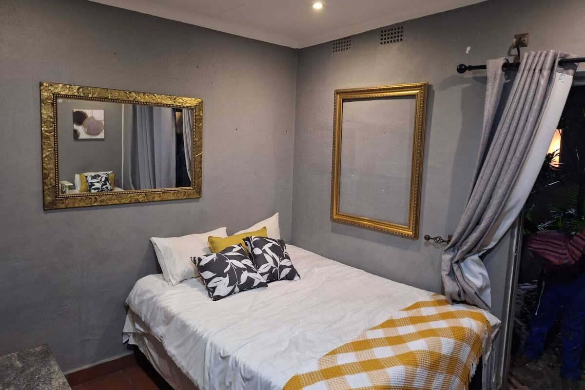 Quarto com cama, duas espelhos e cortina.