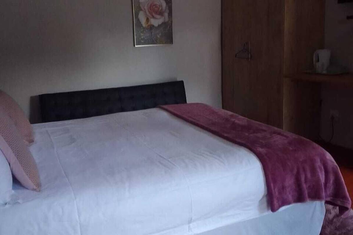 Quarto com cama, guarda-roupa de madeira e um quadro na parede.