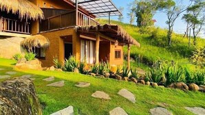Ein zweistöckiges Haus mit einem Reetdach, einem Holzbalkon und einem Steinweg, der zum Eingang führt.