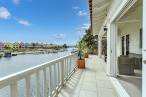 A balcony with a view of a marina and colorful houses across the water.