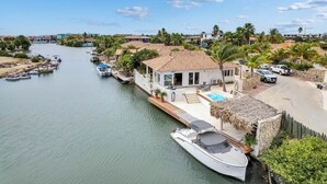 Propiedad frente al mar con muelle, piscina y casa con techo de tejas.