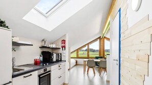 Une cuisine moderne dotée d’une verrière, un coin repas offrant une vue agréable et un mur d’accent en bois.