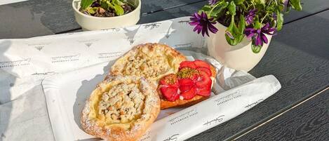A tray with two pastries and a strawberry slice on a table with two potted plants.
