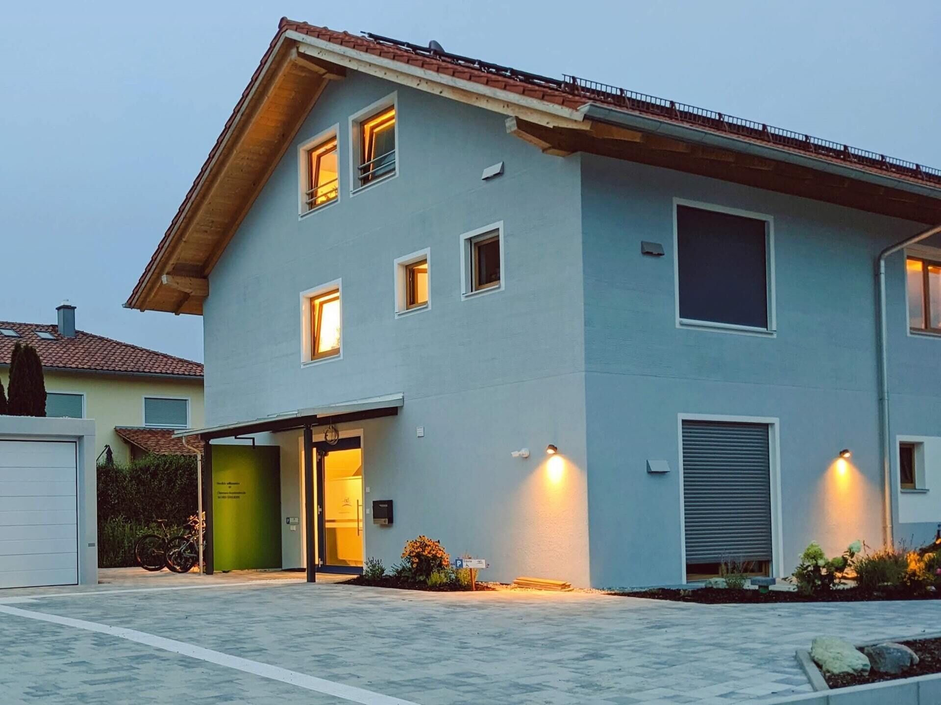 A modern two-story house with a garage, a green door, and a driveway.