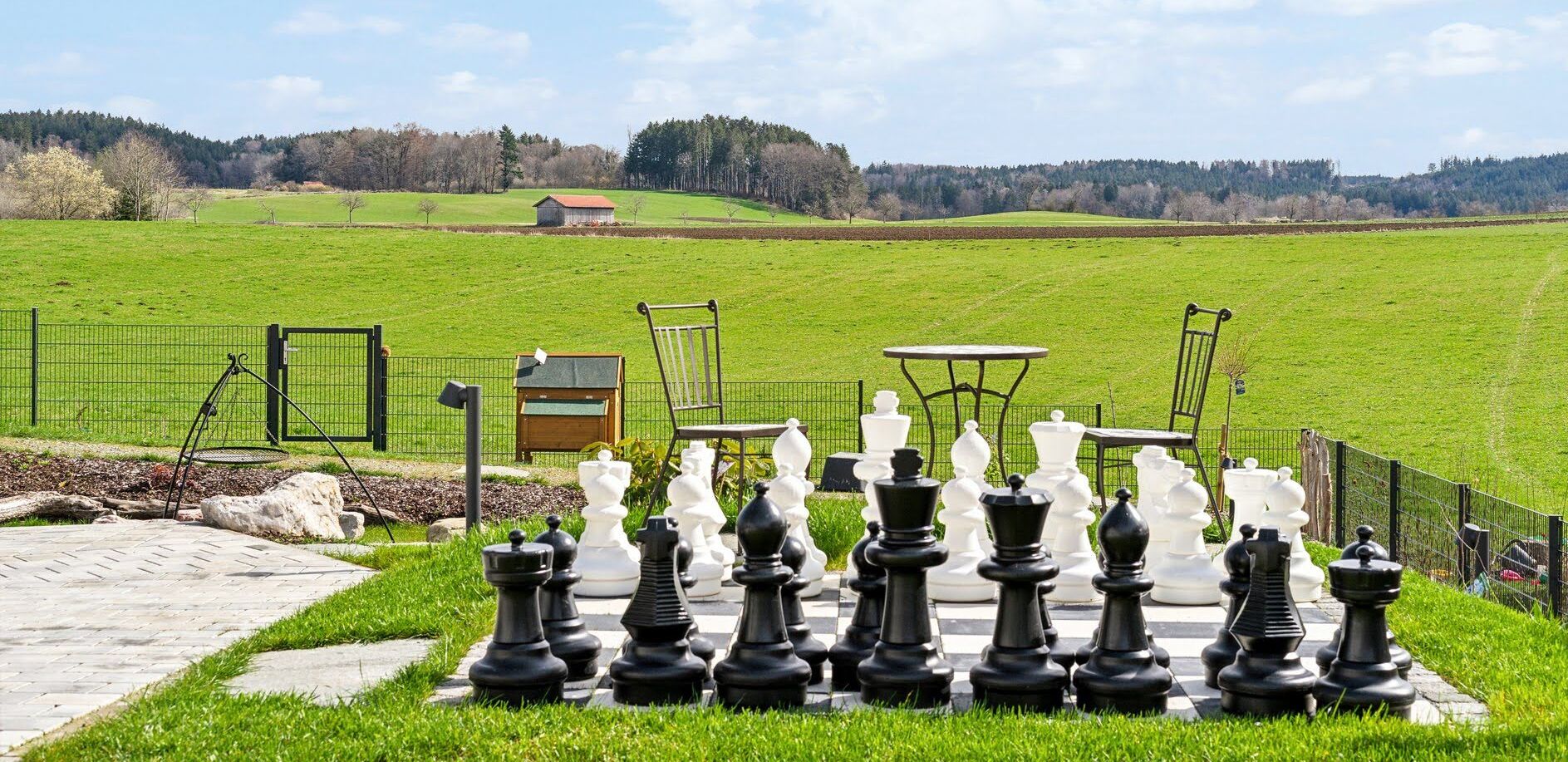 A chessboard set up outdoors with a rural landscape in the background.
