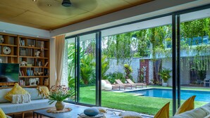 Una sala de estar moderna con un amplio ventanal, una piscina y una estantería bien surtida.