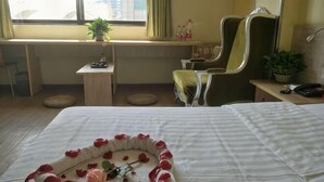 A hotel room with a bed, a desk, a chair, a potted plant, and a window. - Yiyi Chain Hotel (Foshan Sanshui Plaza Branch) (Foshan)
