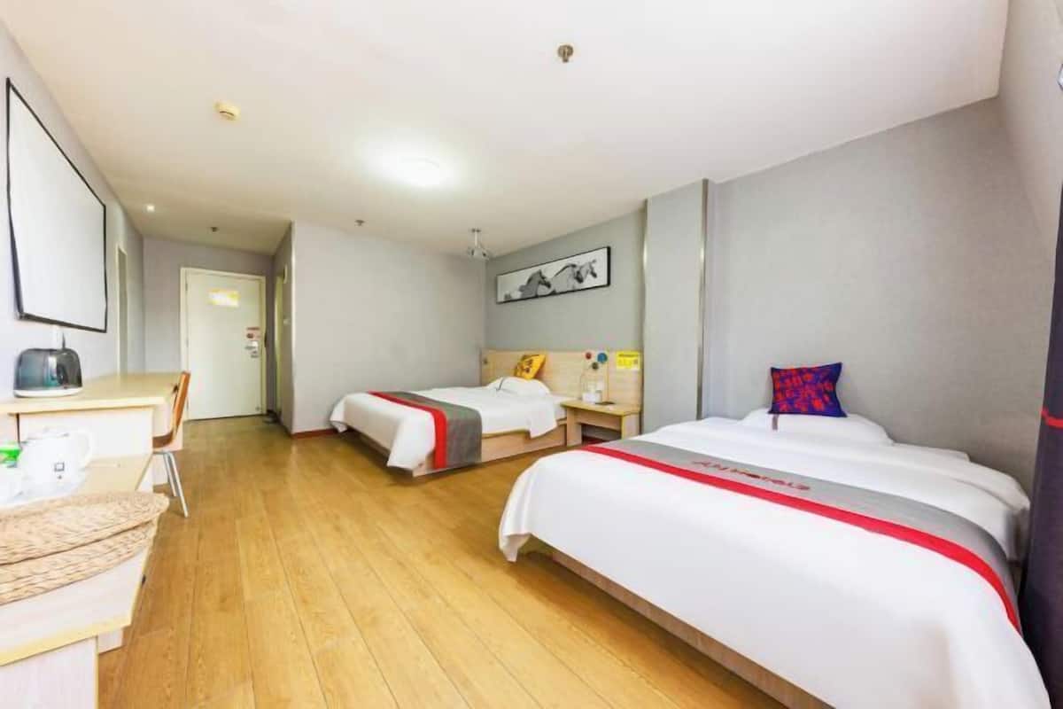 Habitación de hotel con dos camas, un escritorio y una silla.