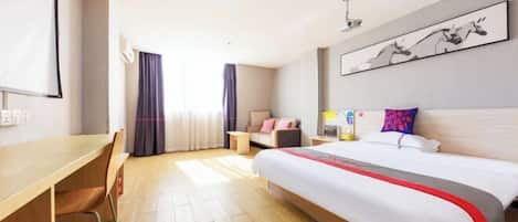 A hotel room with a bed, a desk, a chair, a sofa, a coffee table, and a painting on the wall.