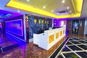 A hotel reception area with a marble reception desk, a purple-lit wall, and a tiled floor. - Yiyi Chain Hotel (Foshan Sanshui Plaza Branch) (Foshan)
