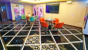 A modern lobby with a black and white tiled floor, a seating area with orange chairs, and a decorative ceiling panel. - Yiyi Chain Hotel (Foshan Sanshui Plaza Branch) (Foshan)