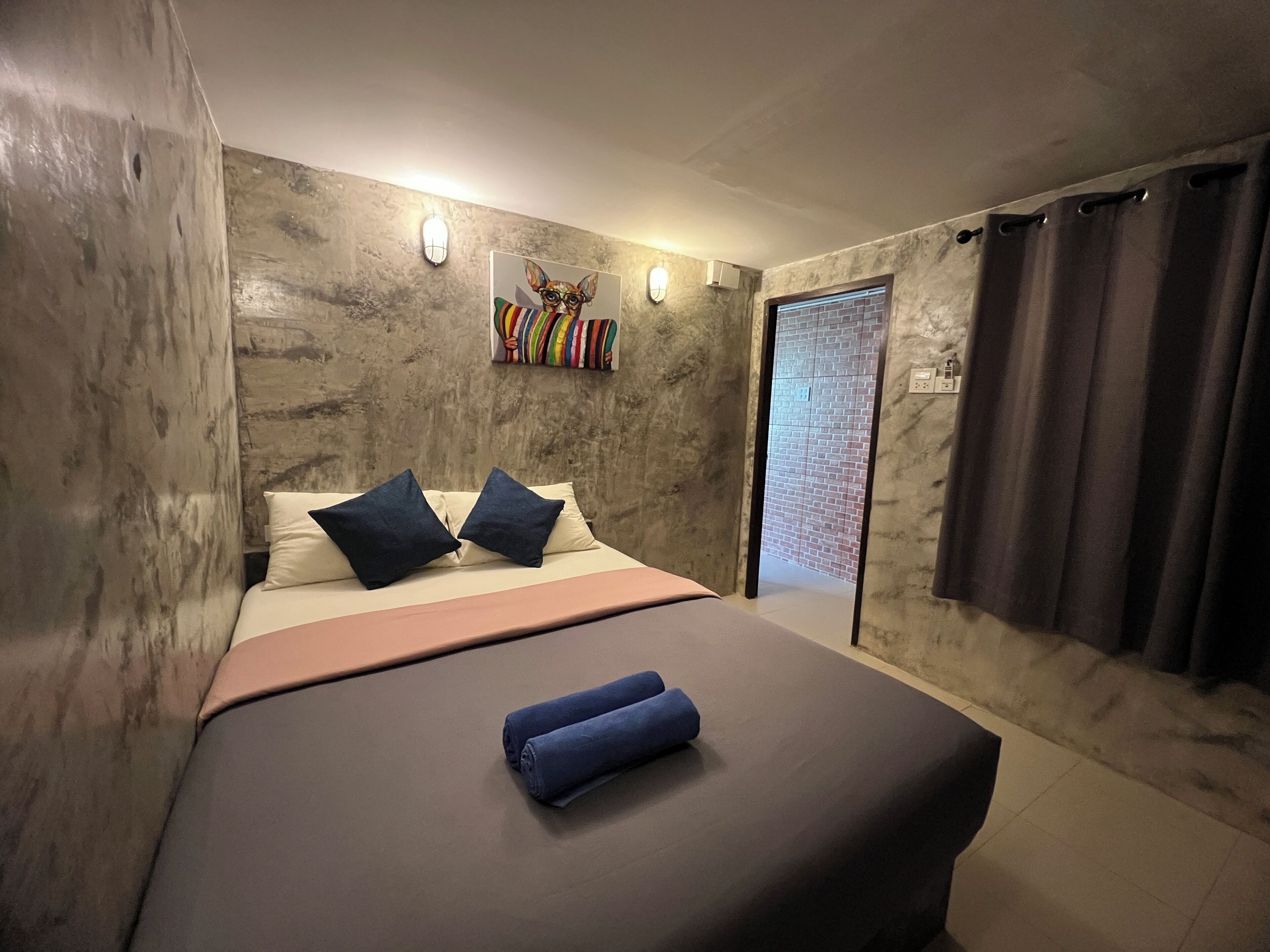 Un dormitorio con cama, almohadas, una obra de arte colgada en la pared y una puerta que da a otra habitación.