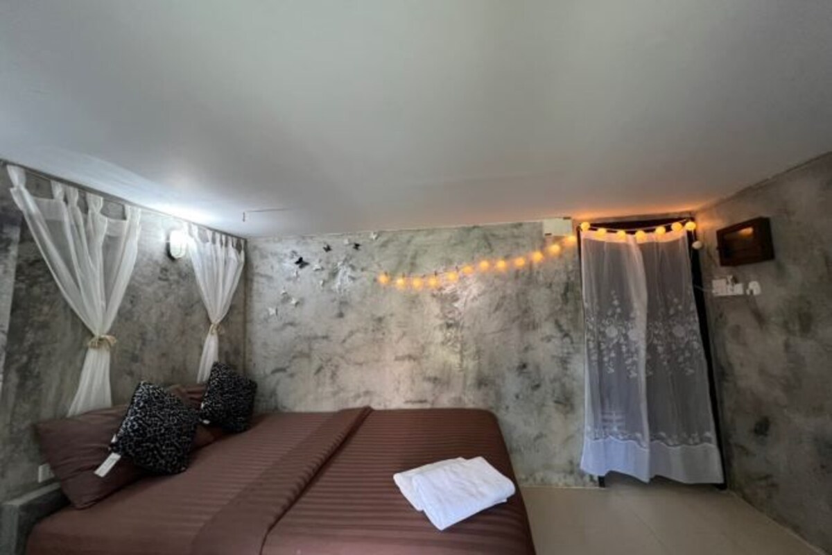 A bedroom with a bed, white curtains, and string lights.