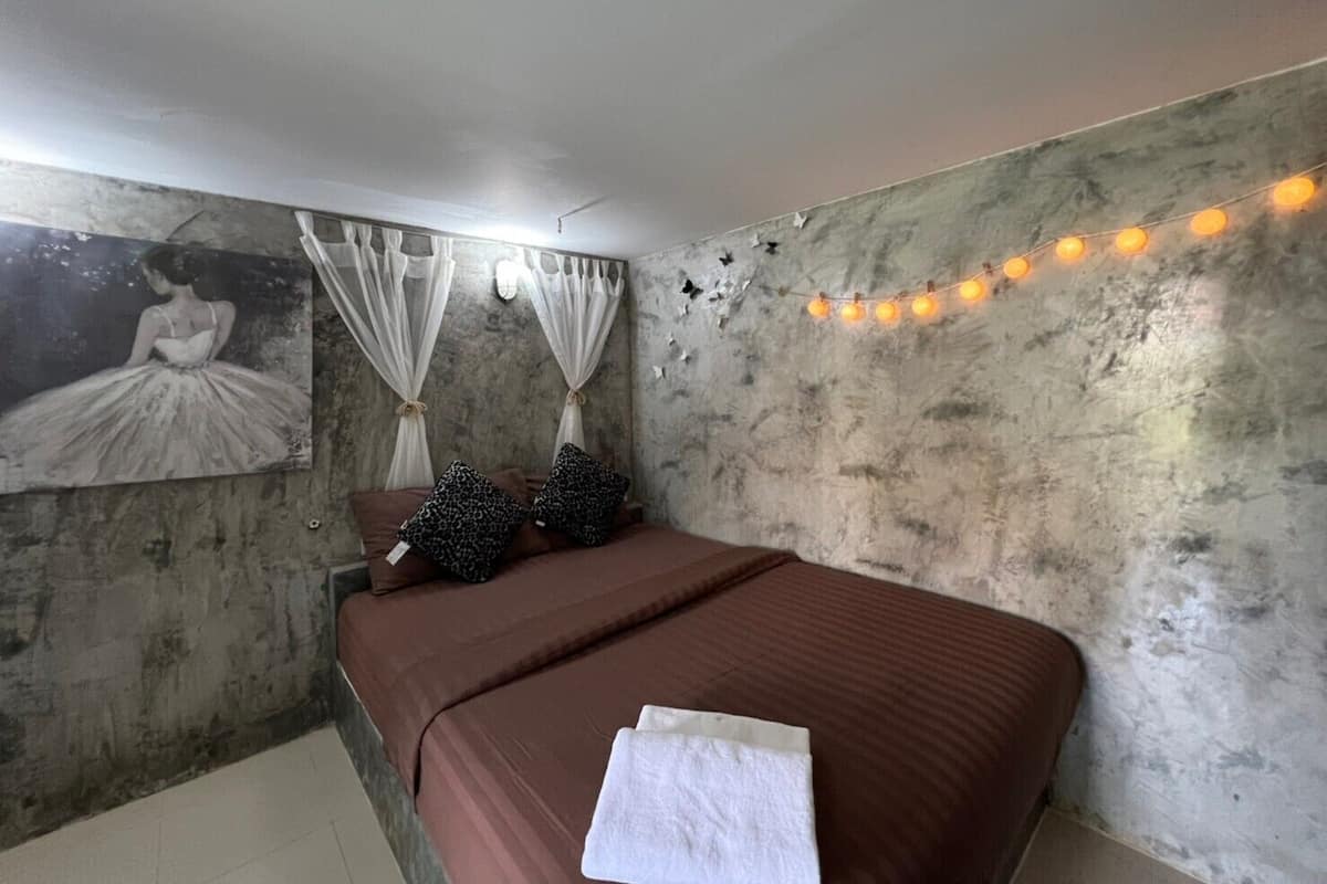Ein Schlafzimmer mit einem Bett, einem Bild an der Wand und Lichterketten.