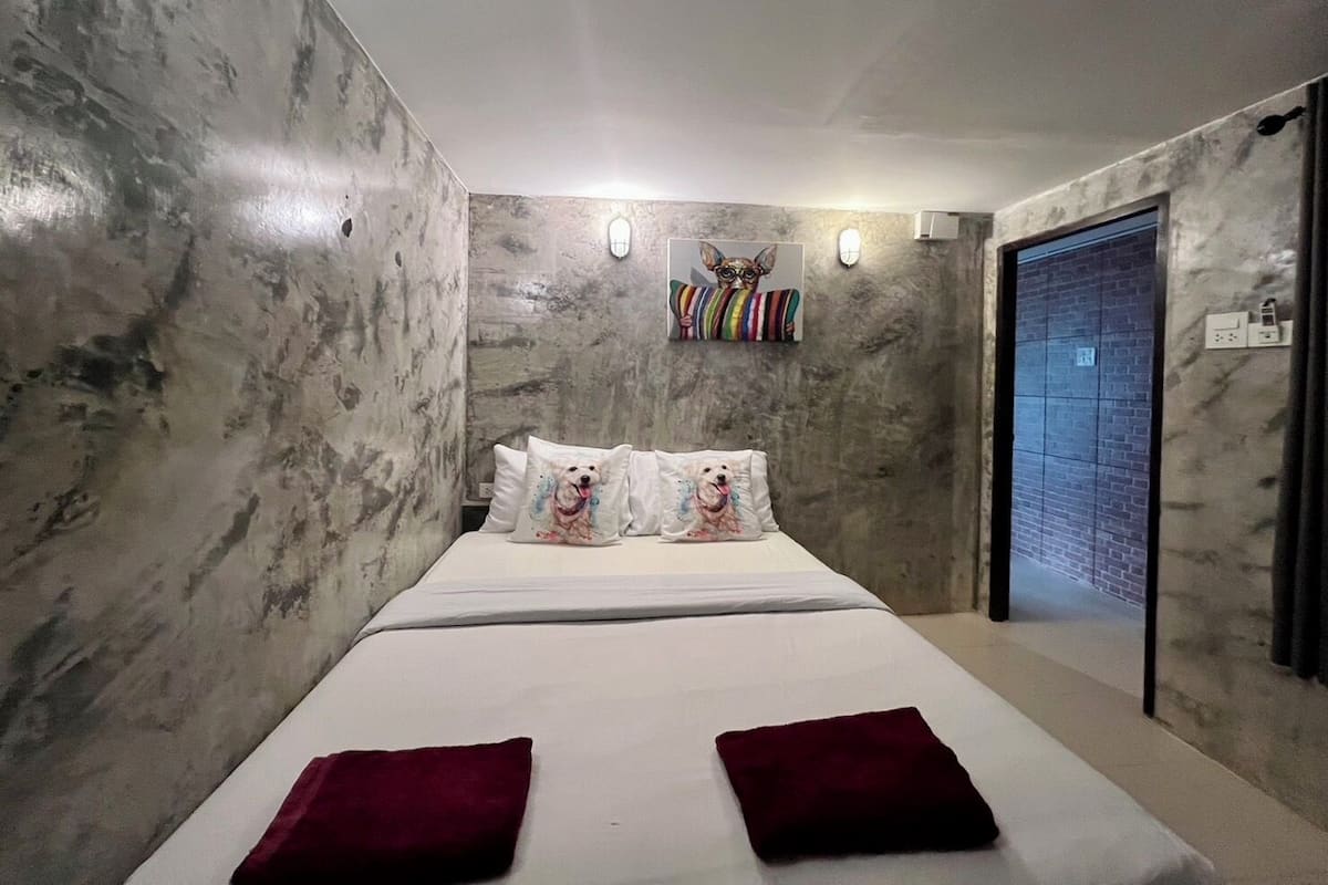 Ein Schlafzimmer mit Bett, Kissen, einer Wandleuchte und einer Tür.