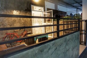A staircase with a metal railing, a red bicycle, and a door leading to a room with a window. - Baan Bua Talay (Rayong)
