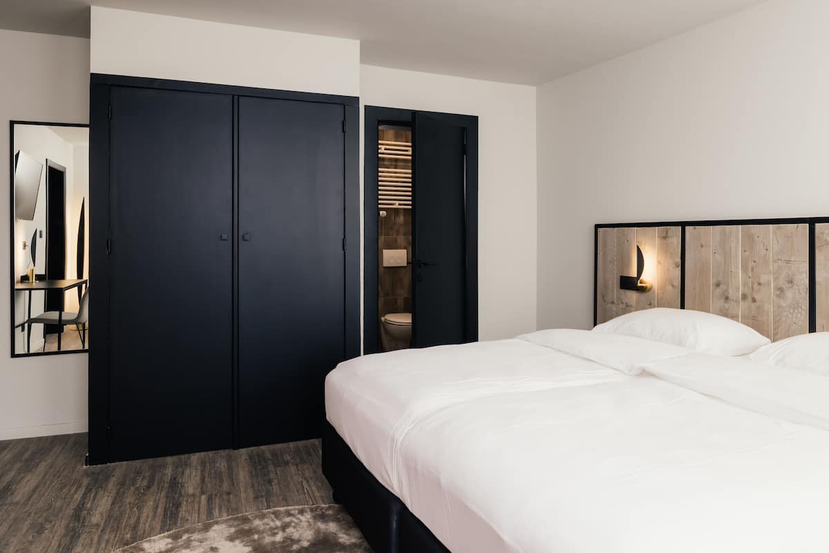 Quarto com uma cama, um guarda-roupa e um espelho.