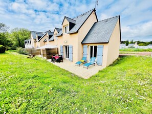 A row of houses with a patio area, outdoor seating, and a grassy landscape. - House in Morgat, Brittany, year-round heated pool, 800m from the sea. (Crozon, Morgat)