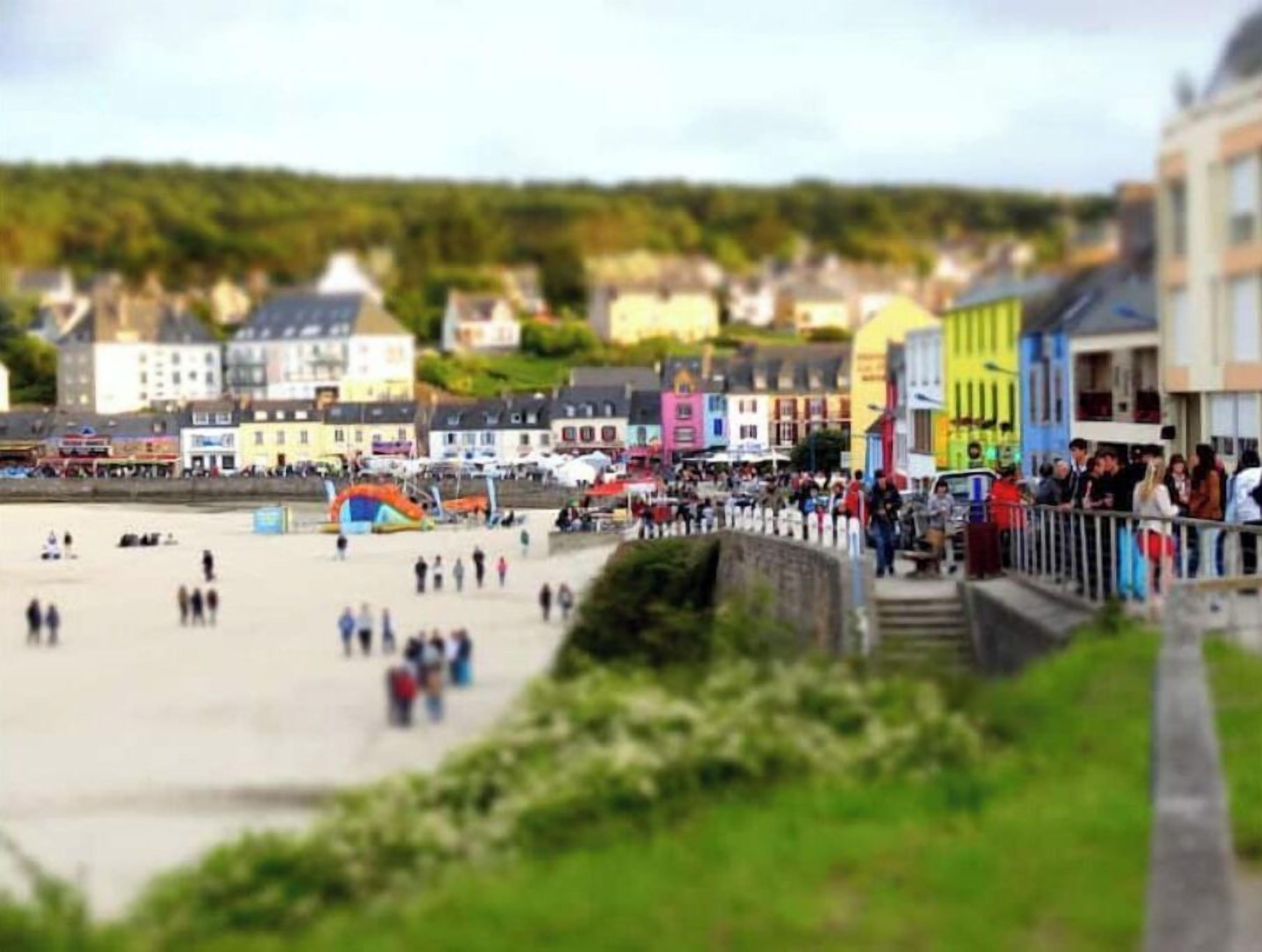 A coastal town with colorful buildings, a sandy beach, and a promenade.
