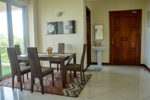 Un comedor con una mesa, sillas, un tapete, un reloj en la pared y una puerta que da a un baño.