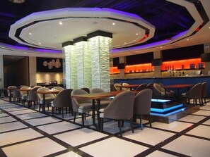Un restaurante moderno con zona de bar, diversas opciones de asientos y un diseño de techo llamativo.