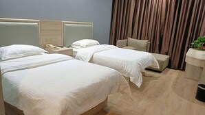 A hotel room with two beds, a bedside table with a phone, a small table with a plant, and a curtain. - Greentree Inn Hebi Hengshan Road Business Hotel (Hebi)