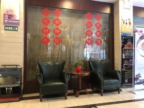 Un vestíbulo con dos sillones de cuero, una mesita con una maceta roja y una pared grande decorada en rojo.