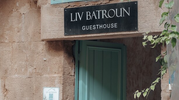 A guesthouse entrance with a sign reading "LIV BATROUN GUESTHOUSE" and a contact number. - Charming condo at the heart of Batroun old souk (Batroun)