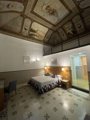 A hotel room with a bed, bedside tables, a desk, and a ceiling with decorative artwork. - Costantinapoli 27 (Naples)