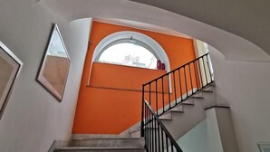 A staircase with a black railing leading to a landing with an arched window. - Costantinapoli 27 (Naples)