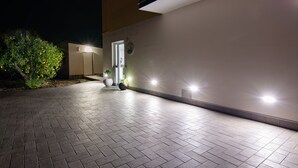 A paved walkway leading to a building entrance at night, with outdoor lighting and potted plants. - "THE DREAM" among lemon groves and one of Italy's Most Beautiful Villages 5 minutes from the sea (ROCCA IMPERIALE)
