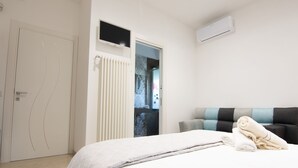 A bedroom with a bed, a radiator, an air conditioning unit, and a door leading to another room. - "THE DREAM" among lemon groves and one of Italy's Most Beautiful Villages 5 minutes from the sea (ROCCA IMPERIALE)