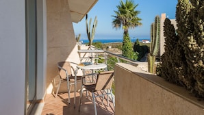 An outdoor patio with a table and chairs, overlooking a coastal landscape with cacti and a palm tree. - Pontalaia Apartamentos Turisticos (Vila do Bispo)