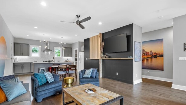 A modern living room with a sofa set, a coffee table, and a TV mounted on the wall.