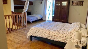 Een slaapkamer met een bed, een houten kledingkast, een nachtkastje en een trap.