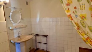 Een badkamer met een wastafel, spiegel en douchegordijn.