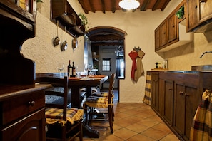 A cozy kitchen with wooden cabinets, a dining table set for four, and a window with a view. - House Chez Paul (Massarosa)