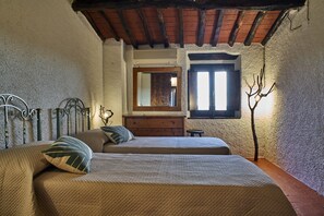 A bedroom with two beds, a wooden dresser, a mirror, and a window with a view of the outside.
