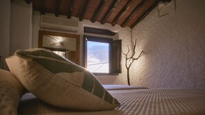 A cozy room with a bed, a window, and a bare tree branch decoration. - House Chez Paul (Massarosa)
