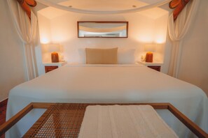 A bedroom with a large bed, two bedside lamps, a mirror, and a wooden headboard.