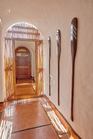 A hallway with a wooden door and three wooden paddles on the wall.