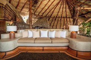 A room with a thatched roof, a sofa with cushions, and two bedside lamps. - La Villa Luz (Zihuatanejo)
