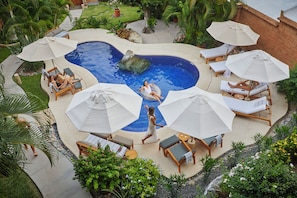 A swimming pool with lounge chairs and umbrellas, surrounded by greenery. - La Villa Luz (Zihuatanejo)