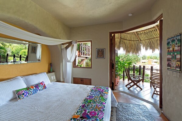A bedroom with a bed, a window, a door leading to a balcony, and a chair. - La Villa Luz (Zihuatanejo)